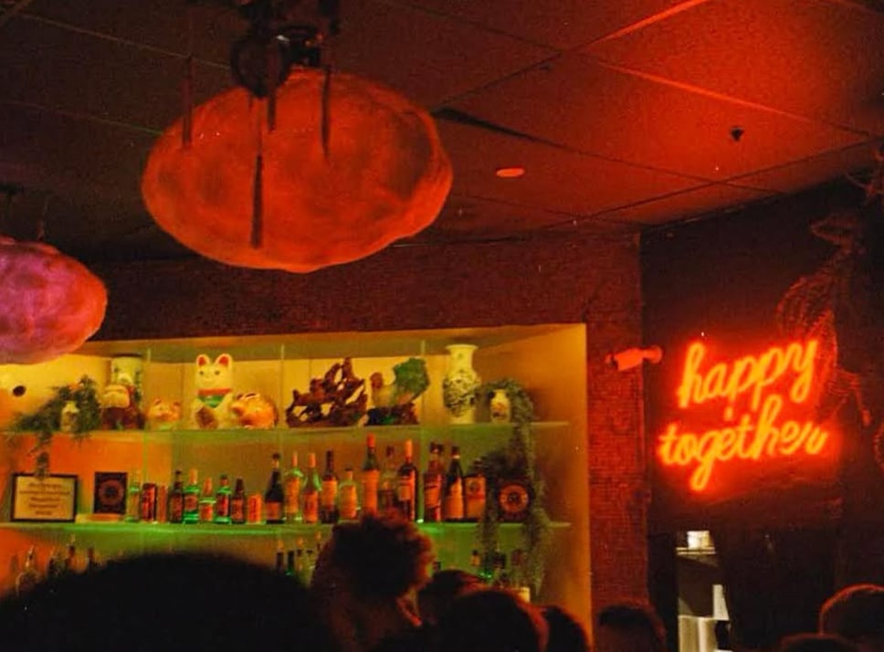A sign that reads 'happy together' within a crowded bar scene