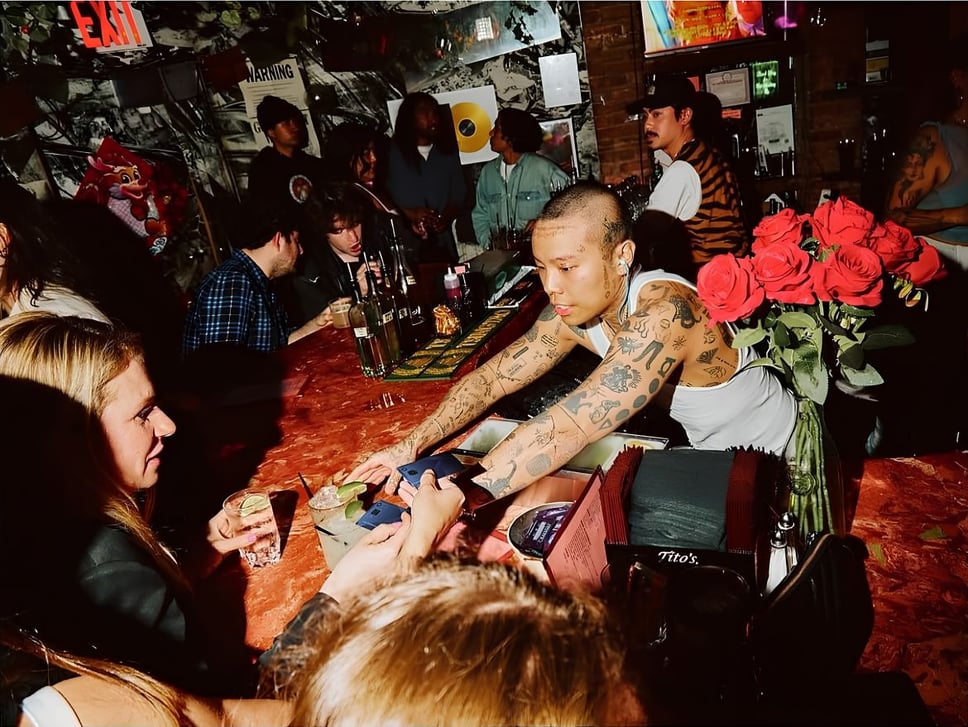 A crowded scene at the Brooklyn location of Mood Ring, with a bartender working a busy night taking credit cards from patrons and providing drinks