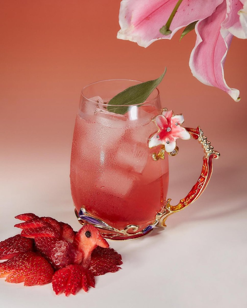 A pink signature cocktail at Mood Ring, professional product photography with a flower having in the upper-right hand corner.