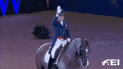 A rider waves while riding a horse.