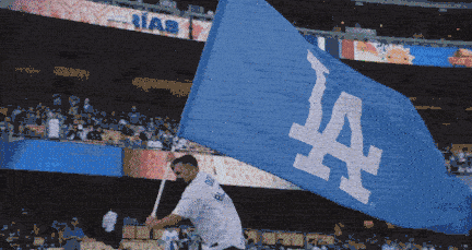 A large blue LA Dodgers flag waves on the field.