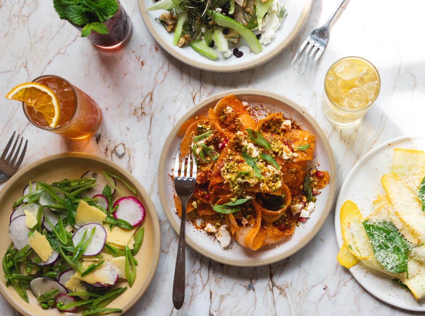 Pasta, salads, and cocktails on a table at Bar Fortuna in Santa Monica.