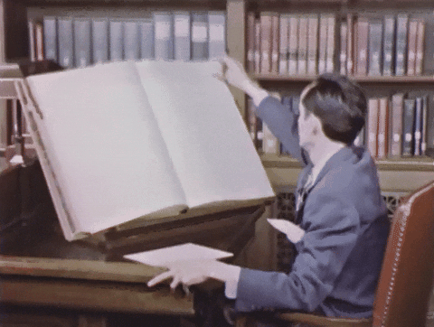 Vintage footage of a reader flipping through a giant book in a library.