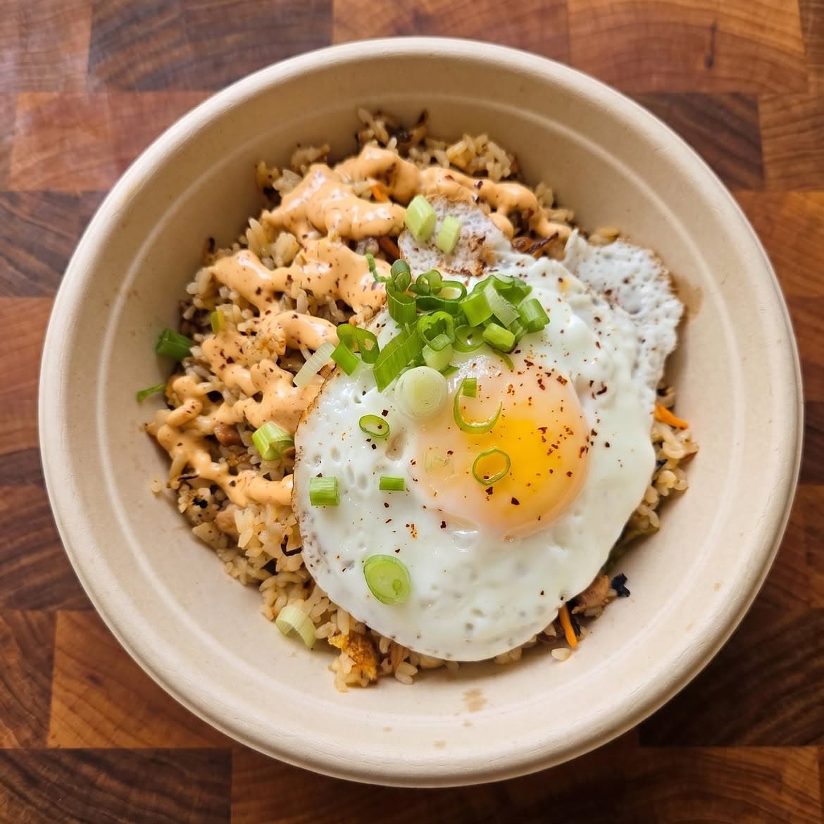 A grain bowl at Dobo in Glendale topped with a fried egg, sliced scallions and a drizzle of spicy mayo.
