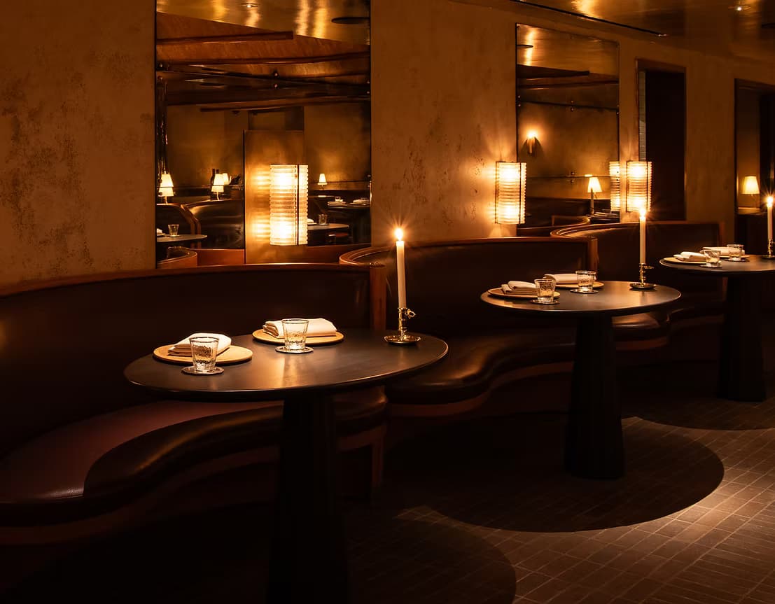 The candlelit dining room at Lielle in Pico-Robertson, with curved leather banquettes and warm sconce lighting.